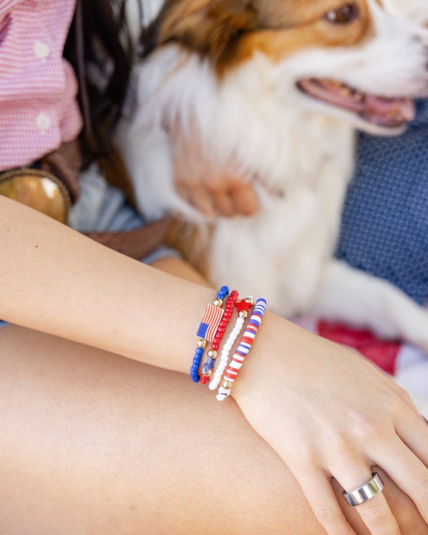 Person wearing colorful beaded bracelets on a dog's lap