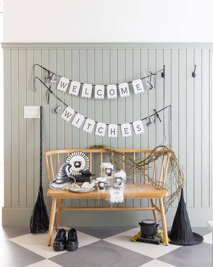 Halloween-themed decor with a 'Welcome Witches' banner, broom, and witch hats on a checkered floor.