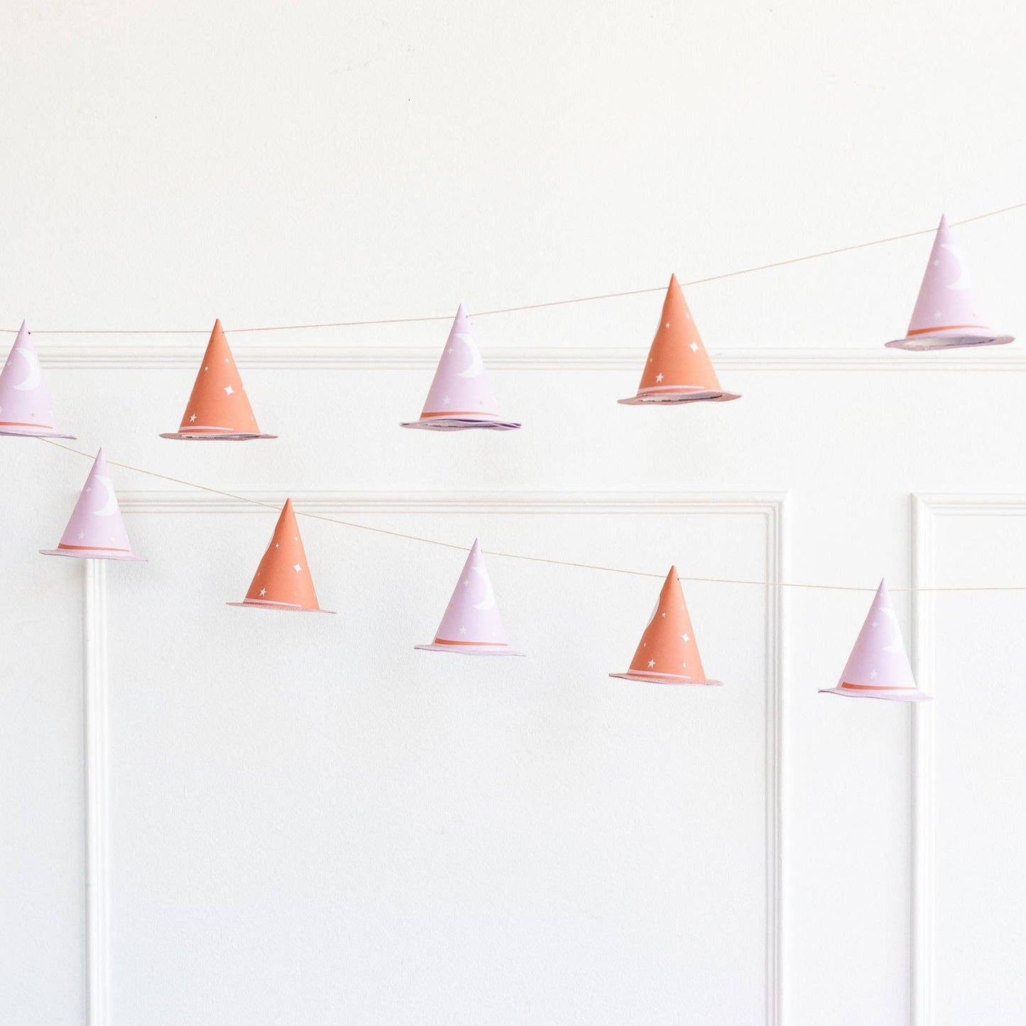 String banner with pink and white cone-shaped 3D witch hats on a white background with elegant moldings.
