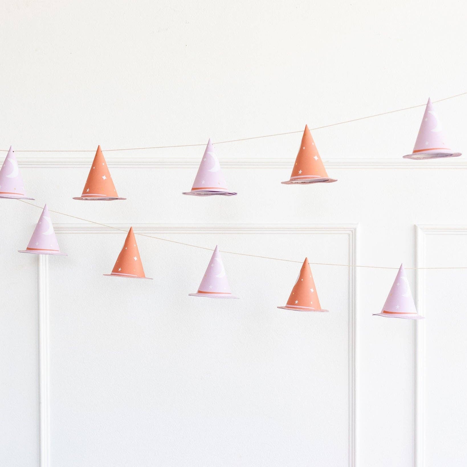 String banner with pink and white cone-shaped 3D witch hats on a white background with elegant moldings.