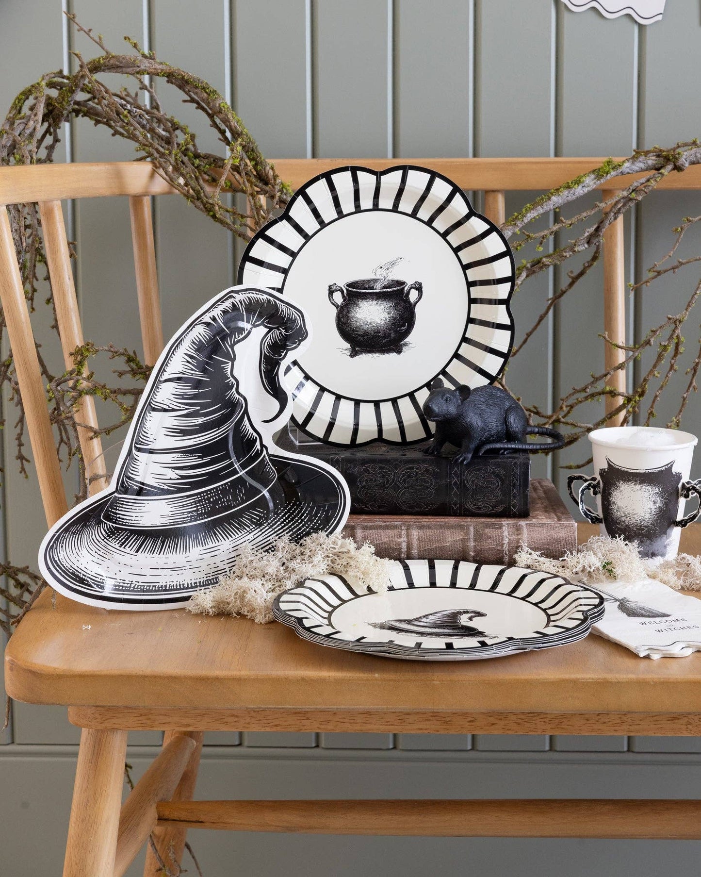 Halloween-themed table setting with decorative plates and a witch hat on a wooden table.