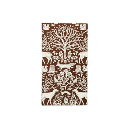 Patterned paper guest towel napkin with forest animals and trees on a brown background.