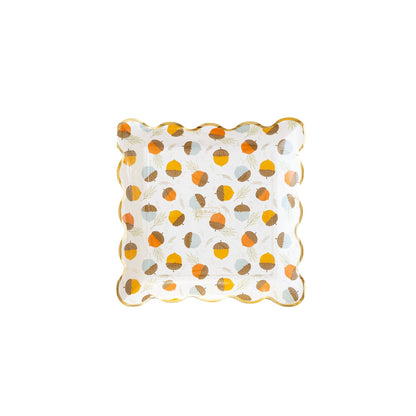A scalloped paper plate with an acorn-scattered print and gold foil trim.
