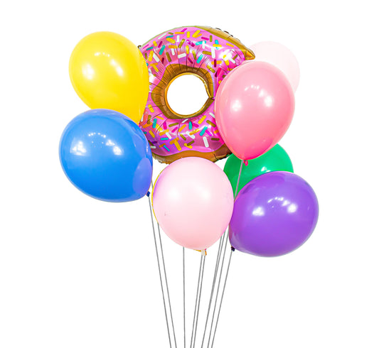 A cluster of assorted colorful balloons , including one to resemble a donut with a hole in the center, with ribbons attached to the bottom.