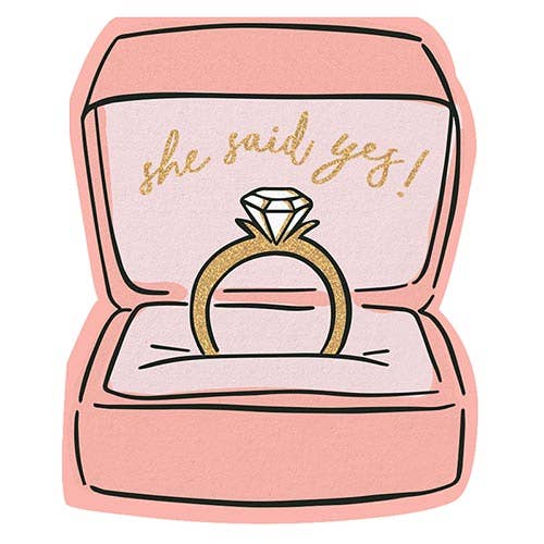 A die cut paper napkin shaped like a ring box with 'She Said Yes' text and a diamond ring illustration, indicating it is for a bridal shower or engagement party.