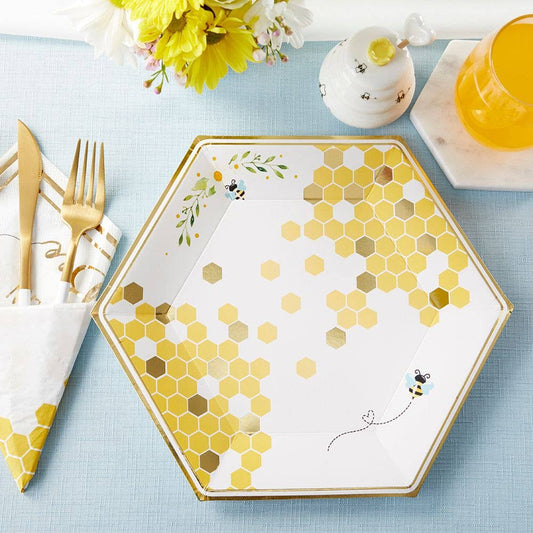 A set of 9-inch premium paper plates with a honeycomb pattern and gold foil accents, displayed on a table with cutlery and decorative items.