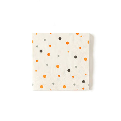 A square cocktail napkin with orange and black polka dots on a white background.